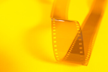 Translucent fragment of 35 mm movie on yellow surface.