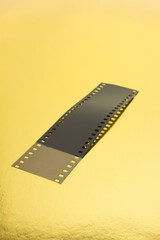 Fragment of 35 mm film on golden surface.