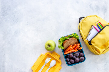 School lunch box with food and backpack, top view