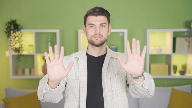 Young man making no, stop, no gestures towards the camera with his hands and gestures.
Young man jes makes negative gestures towards the camera, using his gestures and hands.

