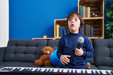 Down syndrome kid singing song sitting on sofa at home