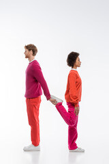 side view of interracial couple in magenta color clothes showing n letter on white background.