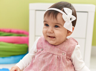 Adorable hispanic baby smiling confident sitting on floor at kindergarten