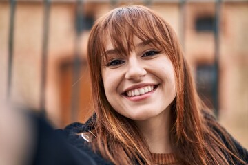 Young woman smiling confident making selfie by the camera at street