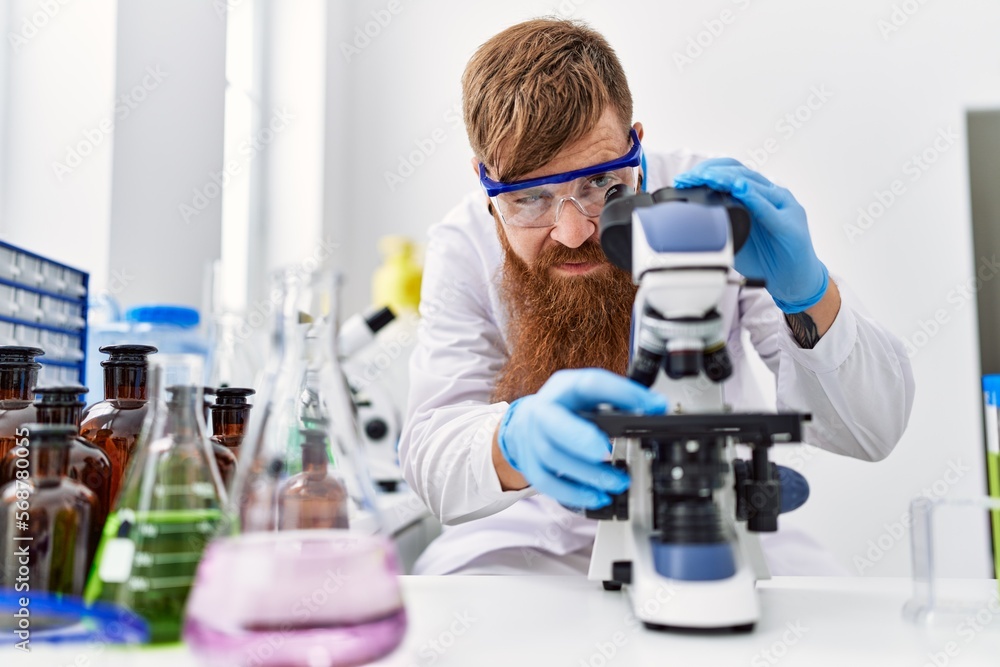 Canvas Prints young redhead man wearing scientist uniform using microscope at laboratory