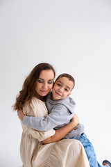  Boy preschooler and mother smile and hug on gray background in photo studio