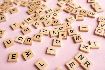 Top view of square wooden tiles with the English alphabet lying on a pink background. The concept of developing thinking, grammar, back to school, learning