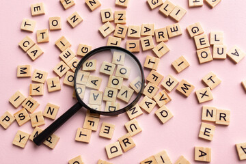 Square letter tiles with magnifying glass against pink background. Search for words and information...