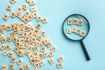 Square letter tiles with magnifying glass against blue background. Search for words and information...
