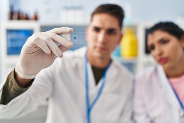 Man and woman scientists partners analysing sample at laboratory