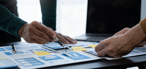 ux developers and ui designers, data researchers brainstorm on  tabletop mobile app interface wireframe design with client summary color codes the modern office Creative Digital Development Agency.