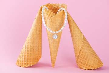 Necklace or choker made of pearls with a mother-of-pearl pendant in a waffle cone on a pink...