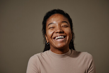 Candid black young woman laughing neutral beige background in studio