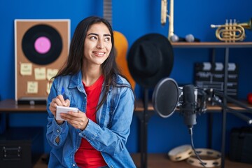 Young hispanic girl artist composing song at music studio