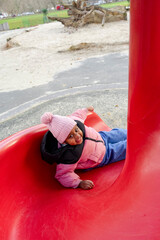 Girl (2-3) going down on slide in playground