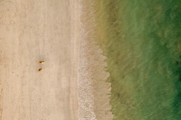 Indonesia, Lombok, Aerial view of men walking with surfboards on beach