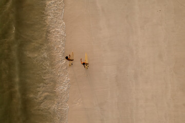 Indonesia, Lombok, Aerial view of surfers walking on beach 