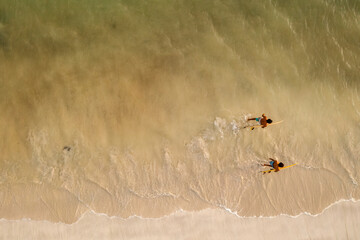 Indonesia, Lombok, Aerial view of surfers walking in sea