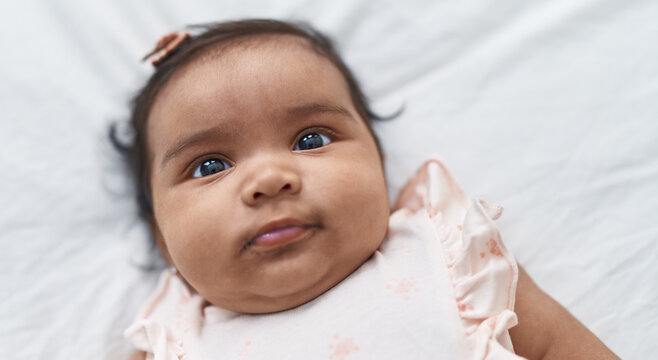 African american baby lying on bed with relaxed expression at bedroom
