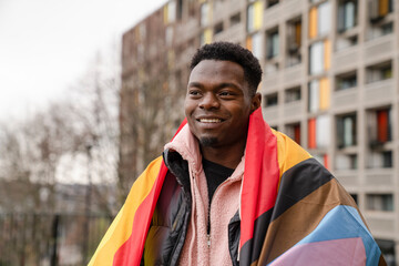 Smiling young man wrapped in progress pride flag