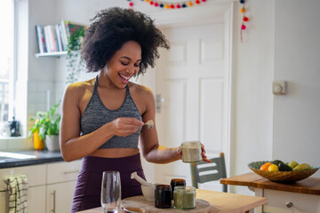 Smiling young woman preparing healthy drink at home