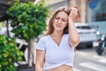 Young blonde woman suffering headache standing at street