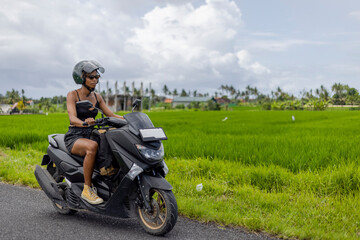 Fototapeta na wymiar Indonesia, Bali, Female tourist on motorcycle road trip