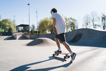 Sportive skater riding skateboard on ramp during training