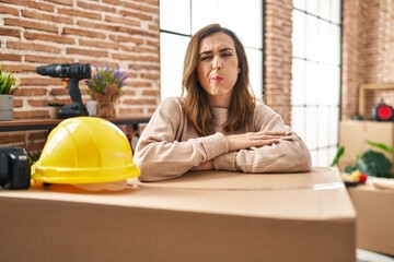 Young woman moving to a new home making fish face with mouth and squinting eyes, crazy and comical.