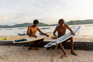 Fototapeta Indonesia, Lombok,�Surfers preparing surfboards on beach at sunset obraz