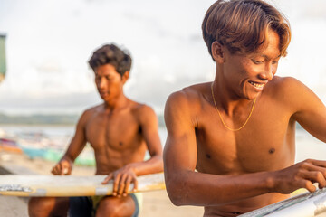 Fototapeta Surfers preparing surfboards on beach at sunset obraz