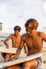 Fototapeta Surfers preparing surfboards on beach at sunset obraz