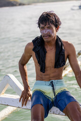 Fototapeta Portrait of male tourist sitting on boat on sunny day obraz