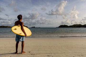Fototapeta Indonesia, Lombok, Surfer with surfboard looking at sea view from beach obraz