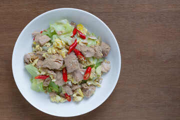 top view of stir fried tuna meat with cabbage and egg in a ceramic dish on wooden table. asian homemade style food concept.