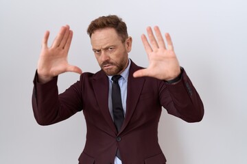 Middle age business man with beard wearing suit and tie doing frame using hands palms and fingers, camera perspective