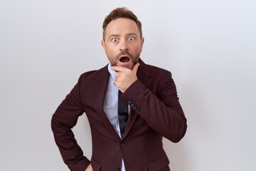 Middle age business man with beard wearing suit and tie looking fascinated with disbelief, surprise...
