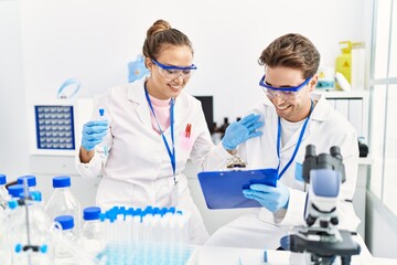 Man and woman wearing scientist uniform working at laboratory