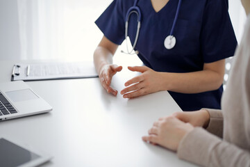 Doctor and patient discussing current health questions while sitting at the table in clinic, jast...