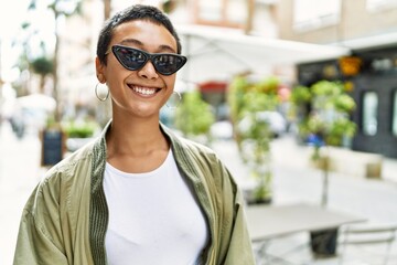 Young hispanic woman smiling confident standing at street