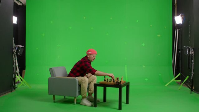 chess player playing chess with an imaginary or virtual opponent on the table. Shot in 4k resolution with green screen background