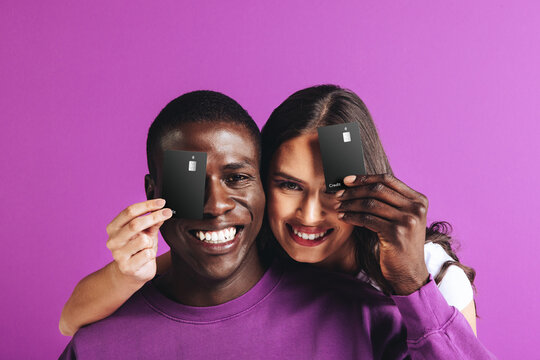 Happy couple holding black credit cards in a studio, recommending electronic banking