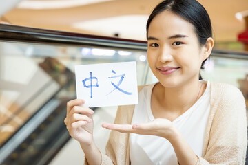 Smiling woman showing Mandarin Chinese vocab flash card, concept of foreign language learning