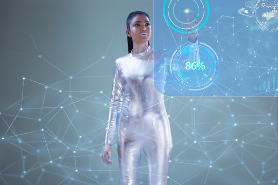A woman wearing silver dress touching a digital Screen standing on a grey backdrop, future technology concept. 