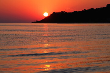 Naklejka premium Peaceful sunset with red sky, sea and mountains