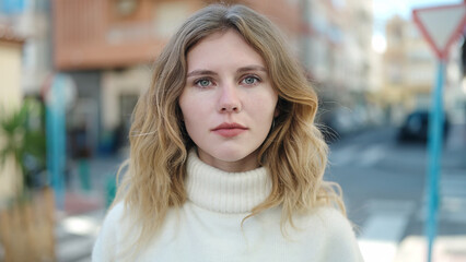Young blonde woman standing with serious expression at street