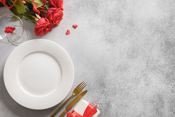 Valentine's day dinner. Romantic table place setting, gift and red rose on gray background. View from above. Copy space.