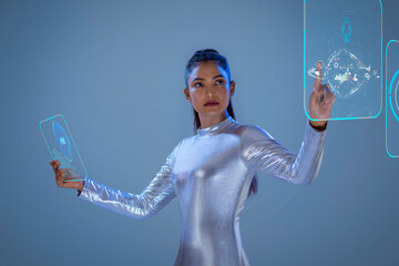 A woman wearing silver futuristic  clothes holding digital tablet, and looking at a virtual screen. A future technology concept