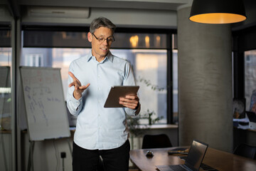 Fototapeta premium Portrait of businessman in office. Man using digital tablet. Businessman having video call..