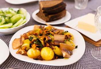 baked potatoes with chanterelles and bacon served with herbs on white plate